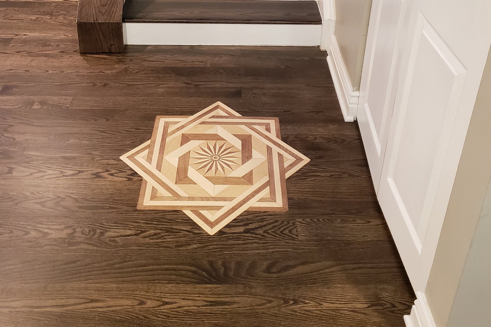 Custom inlaid wood medallion set into a dark-stained oak floor